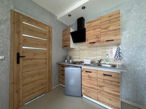 Una cocina con refrigerador blanco y gabinetes de madera. en Apartamenty DandE, en Władysławowo