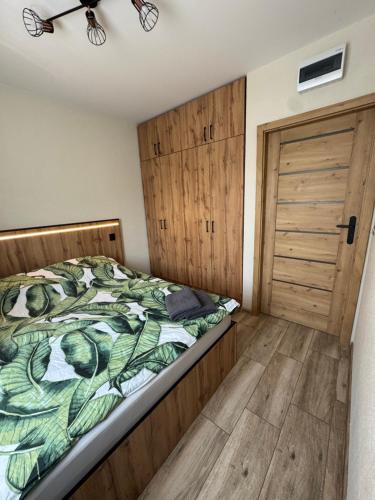 Un dormitorio con una cama y una puerta de madera. en Apartamenty DandE, en Władysławowo