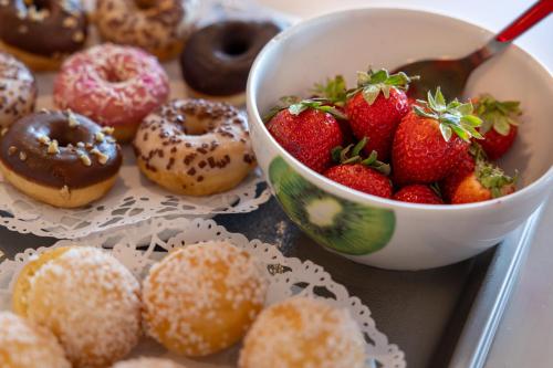 a table with a bowl of strawberries and donuts at Family Golf Hotel in Royan