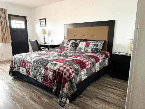 a bedroom with a bed with a red and black blanket at Riverwood Resort on the Gunnison in Delta