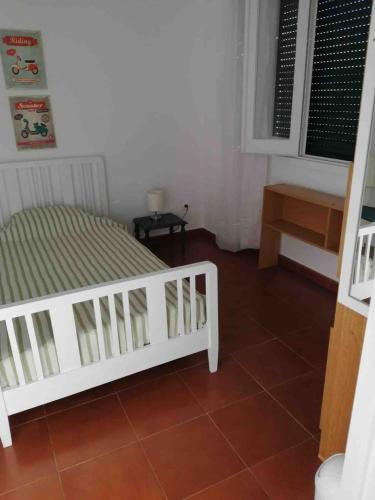 a bedroom with a white bed and a table at GuestReady - Cheerful Ponta Delgada townhouse in Ponta Delgada