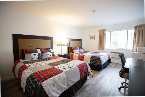 a hotel room with two beds and a desk at Riverwood Resort on the Gunnison in Delta
