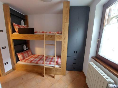 ein Etagenbett aus Holz in einem Zimmer mit Fenster in der Unterkunft Villa Emma in Ponte di Legno