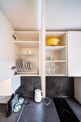 a kitchen with white cabinets with plates and bowls at Hugo apartment in Šiauliai