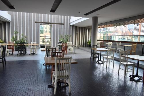 a dining room with tables and chairs and windows at Hotel Holiday Inn Express & Suites Medellin by IHG in Medellín