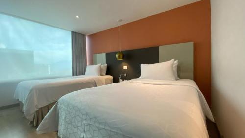 a hotel room with two beds and a large window at Hotel Holiday Inn Express & Suites Medellin by IHG in Medellín