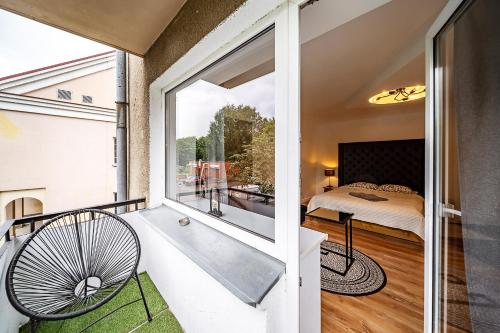 a room with a tub and a bedroom with a window at Hugo apartment in Šiauliai