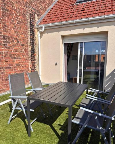 - une table de pique-nique et 2 chaises devant un bâtiment dans l'établissement Le Bleu d'Opale, à Sangatte