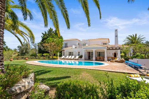 a house with a swimming pool and palm trees at Peaceful 4BR villa on Gramacho golf resort w/ private pool in Lagoa
