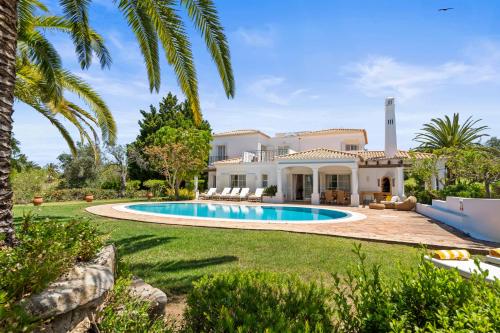 a house with a swimming pool and palm trees at Peaceful 4BR villa on Gramacho golf resort w/ private pool in Lagoa