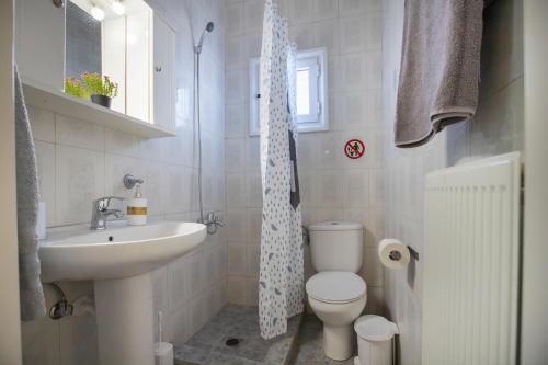 a bathroom with a sink toilet and a shower curtain at My Sunflower in Nea Fokea