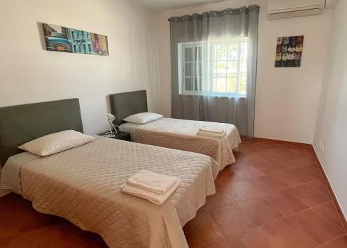 two beds sitting in a room with a window at Casa Campo e Praia by DolceStay - V4 no Meco a 5min da Praia com Jardim & BBQ in Sesimbra