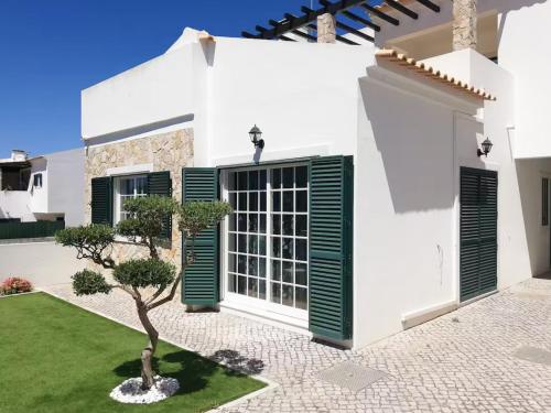 a white house with green shutters and a tree at Casa Campo e Praia by DolceStay - V4 no Meco a 5min da Praia com Jardim & BBQ in Sesimbra