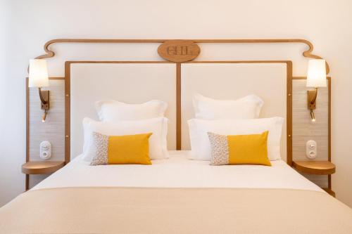 a bedroom with a large white bed with yellow pillows at Grand Hotel Des Lecques; BW Signature Collection in Saint-Cyr-sur-Mer
