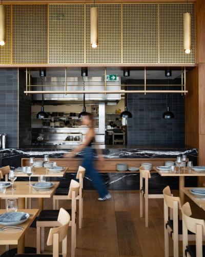 a woman walking in a restaurant with tables and chairs at Crowne Plaza Adelaide by IHG in Adelaide