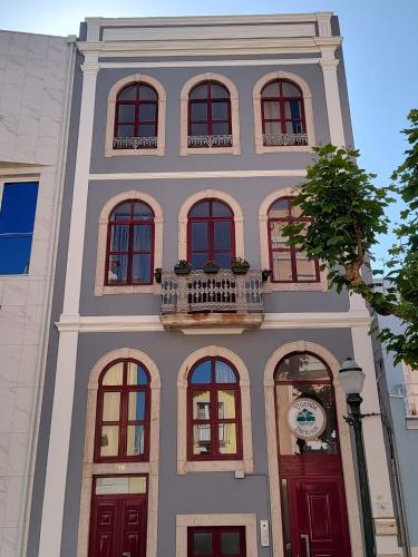 a tall building with red doors and a balcony at Vivenda Liberdade in Figueira da Foz