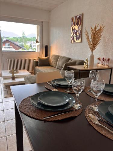 - un salon doté d'une table avec des assiettes et des verres à vin dans l'établissement Le Central parking et 15 minutes à pied du lac, à Thonon-les-Bains