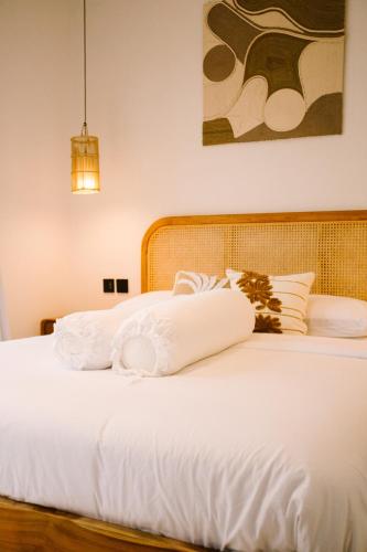 a bed with white sheets and pillows on it at Morroi Villas Tanah Lot in Mantaak