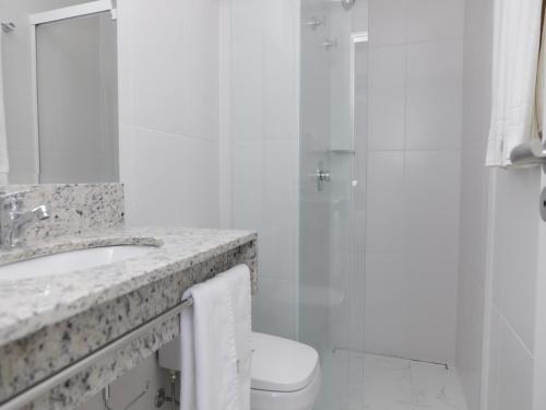 a bathroom with a shower and a toilet and a sink at Slim Curitiba João Bettega in Curitiba