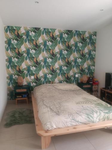 un lit dans une pièce avec un mur couvert de feuilles dans l'établissement Villa au calme, à Tarascon