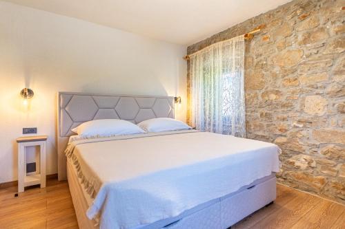 a white bed in a room with a stone wall at Villa Amarie in Štivan