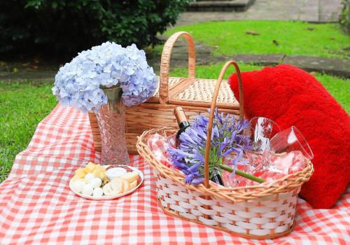 a picnic table with a basket and flowers on it at Pousada Vista do Lago: Lazer e família em Gramado! in Gramado