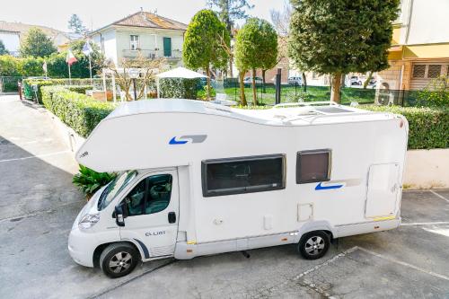 a small white caravan parked in a parking lot at La Locomotiva Rooms in Chiaravalle