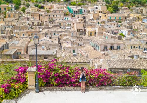 a woman standing on a ledge in front of a city at Casa Aia - Rifugio Naturalistico in Frigintini