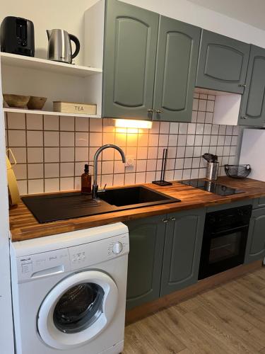 une cuisine avec un évier et une machine à laver dans l'établissement Les horizons de Jules, à Amiens