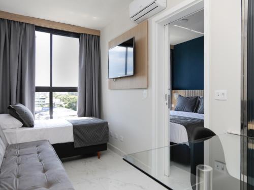 a bedroom with two beds and a tv and a mirror at Slim Curitiba João Bettega in Curitiba