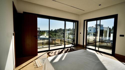 a bedroom with a bed and large glass windows at La Demeure du Bonheur in Hammamet Sud