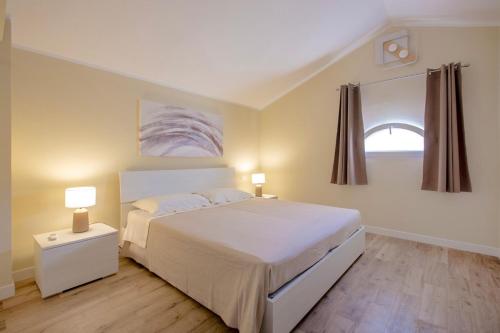 a bedroom with a white bed and a window at Pellicano Suite Apartment in Marina di Grosseto