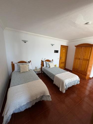 two beds in a room with white walls and wood floors at Apartamento junto al mar La Baja in Santa Cruz de Tenerife