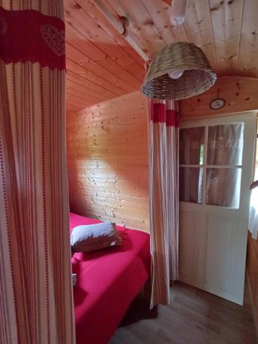 ein Schlafzimmer mit einem rosa Bett in einer Holzhütte in der Unterkunft La Roulotte Authentique au pays de George Sand avec piscine in Mouhers