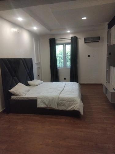 a bedroom with a large bed with white sheets and a window at M&S Luxury Apartment in Lekki