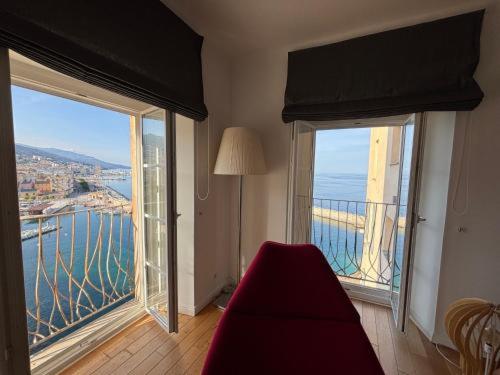 a room with two large windows and a red couch at Appartement MADALLENA in Bastia
