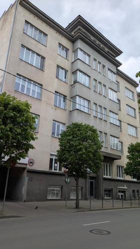 Un gran edificio con un árbol delante. en Kaunas City Centre Apartment Self Check-In & AC, en Kaunas