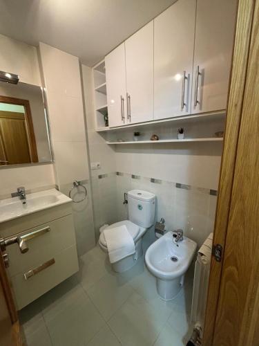 a white bathroom with a toilet and a sink at Alojamiento Morriña in O Pedrouzo