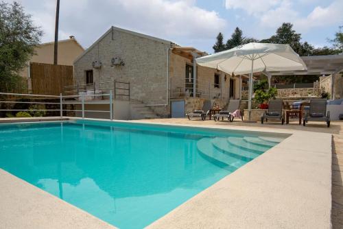 a swimming pool with an umbrella and a house at Villa Rei 3 Bedroom Villa with Pool in Vlachopoulátika