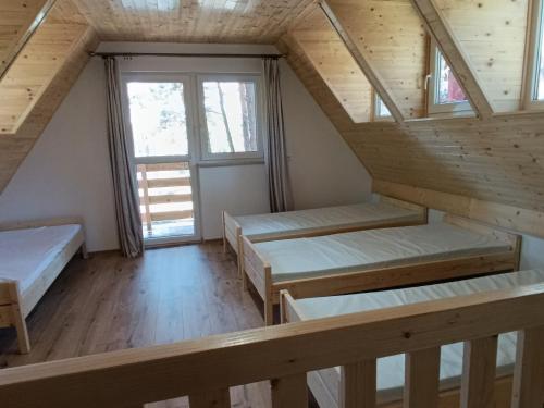 a room with three beds in a wooden house at Domki nad Wierną Rzeką in Bocheniec