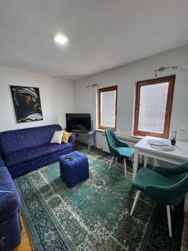 a living room with a blue couch and chairs at Apartmani Ema in Sarajevo