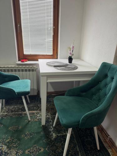 a room with two chairs and a table and a window at Apartmani Ema in Sarajevo