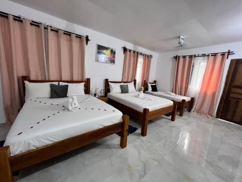 a bedroom with two beds and two windows at Nungwi Beach Front in Nungwi