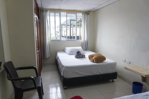 a bedroom with two beds and a chair and a window at Posada Mirador de Filandia in Filandia