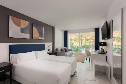 a bedroom with a white bed and a living room at Four Points by Sheraton Costa Blanca Resort in Benidorm