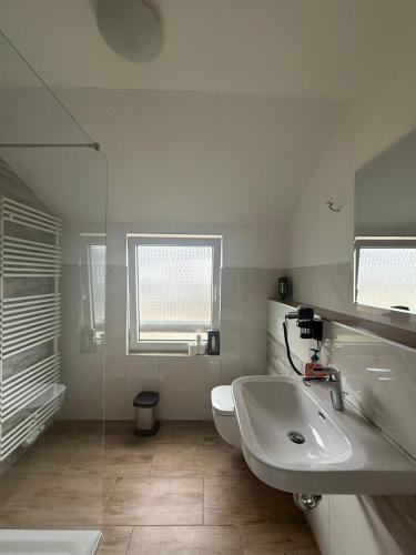 a white bathroom with a sink and a toilet at Odea Ferienhaus in Soltau