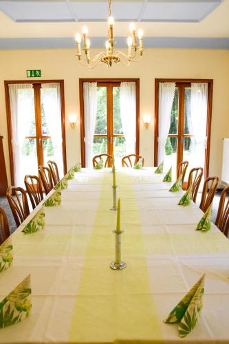 a long table in a room with chairs and a chandelier at Parkhotel Zirndorf in Zirndorf