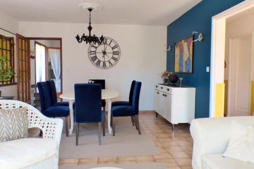 - un salon avec une table, des chaises et une horloge dans l'établissement Beautiful family house with pool, à Six-Fours-les-Plages