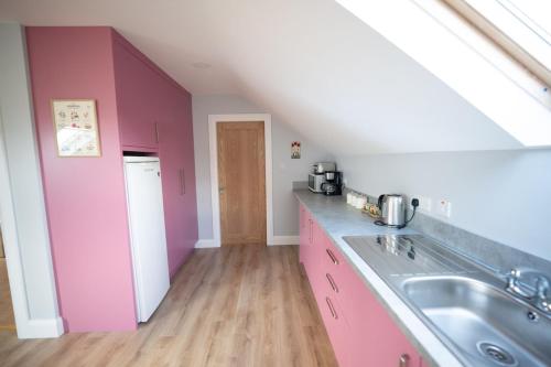 a kitchen with pink cabinets and a sink at The Swilly Suite in Castlequarter