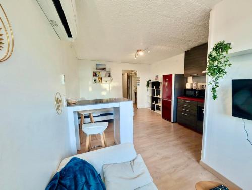 un salon avec un canapé blanc et une cuisine dans l'établissement Carnon Port - Studio, Clim & Parking, à Mauguio